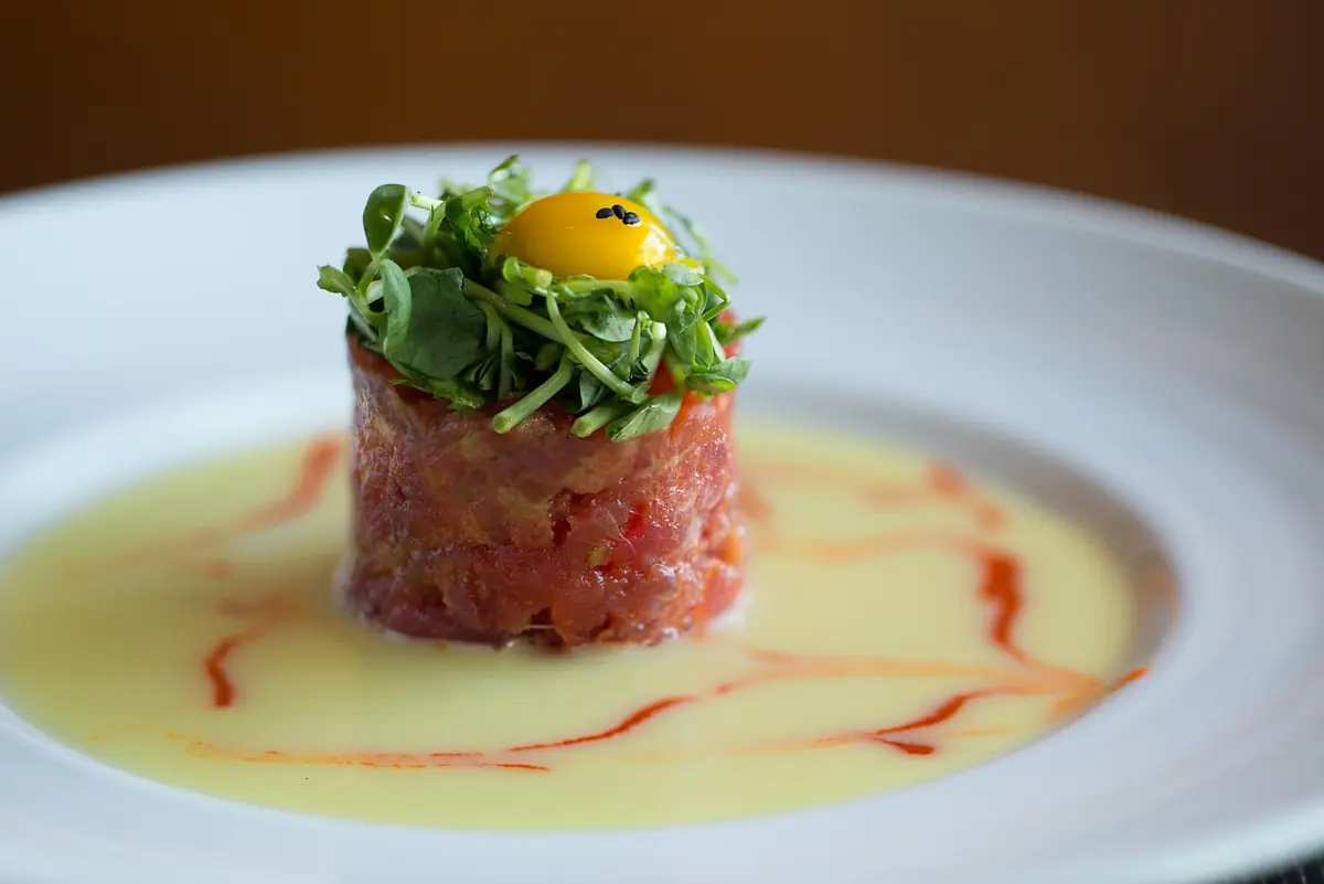 Tuna tartare tower topped with greens and a quail egg yolk