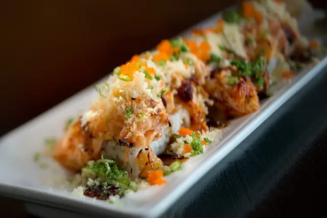 Specialty roll covered in crunchy flakes, masago and sauces