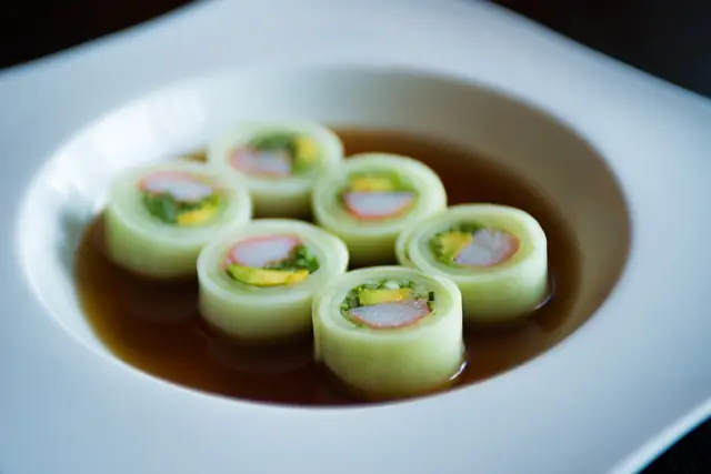 Cucumber-wrapped rolls served in a light sauce