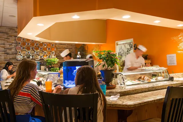 Guests seated at the sushi bar in the bright orange dining room