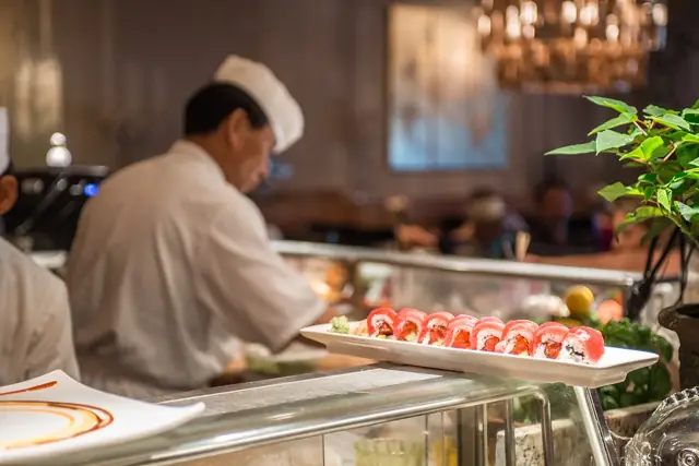 Sushi chef preparing rolls behind the sushi bar