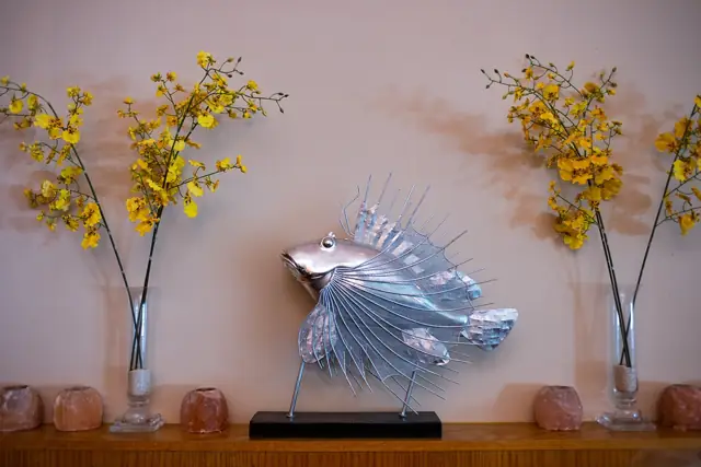 Silver fish sculpture framed by yellow orchid sprays