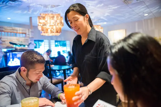 Server bringing drinks to guests at their table