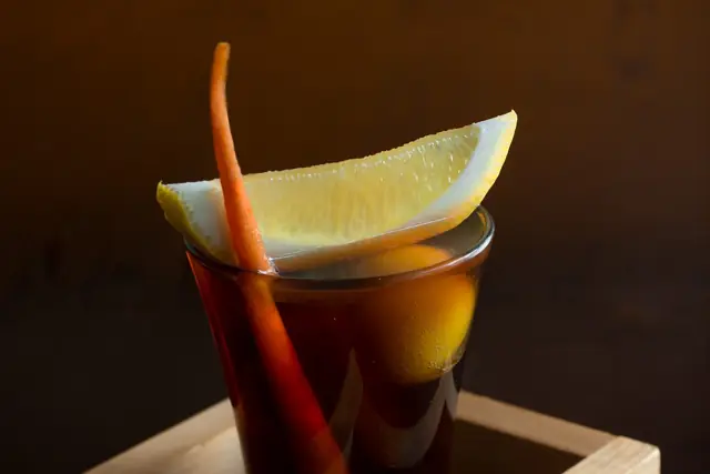 Amber drink garnished with lemon, served in a wooden box