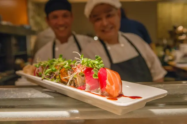 Two sushi chefs presenting a sashimi platter