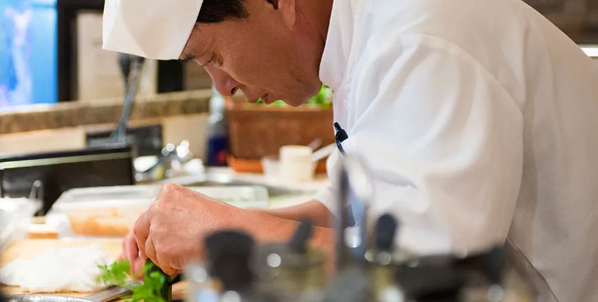 Chef Lee carefully plating a dish at the sushi bar